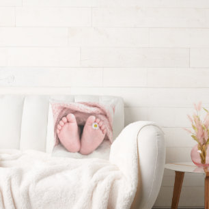 Voetjes van een babymeisje met een witte madeliefj kussen