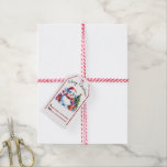 Vrolijk kerstfeest label met een sneeuwpop en cade cadeaulabel<br><div class="desc">Een heerlijk kerst label is voorzien van een lachende sneeuwman in een rood pet,  met een koffiekopje. Rondom hem zijn levendige geschenken en een versierde boom,  perfect voor vakantie gifting.</div>