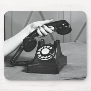 Vrouw die de telefoon oppakt, dicht bij de hand muismat