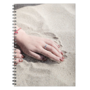 Vrouw die op wit zand ligt notitieboek