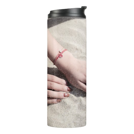 Vrouw die op wit zand ligt thermosbeker (Gedraaid links)