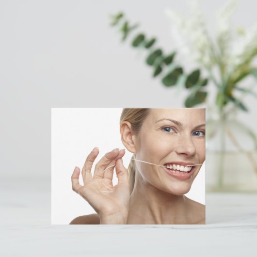 Vrouw tegen witte achtergrond tanden met flossing, briefkaart (Staand voorkant)