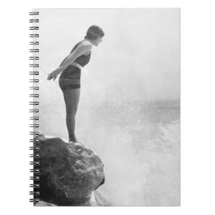 Vrouw zwemmer op een rots boven het crashende surf notitieboek