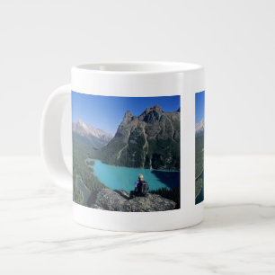 Wandelaar met uitzicht op turkooiskleurig meer grote koffiekop