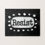 Weersta de puzzel<br><div class="desc">Vetgedrukte tekst met de tekst "Resist" is gecentreerd tegen een zwarte achtergrond. De zwarte tekst bevindt zich op een witte rechthoek met grote getextureerde witte stippen eromheen,  wat een speels contrast biedt tegen de achtergrond van de effen kleur.</div>