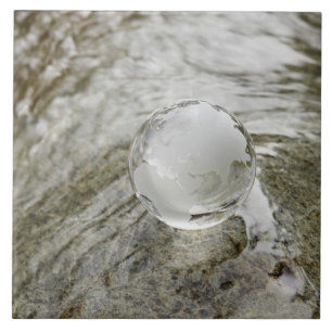 Wereldbol van glas op de waterstroom tegeltje