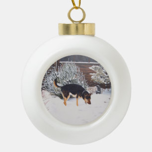 Wintersneeuwscène met schattige zwarte en geelbru keramische bal ornament