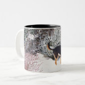 Wintersneeuwscène met schattige zwarte en geelbrui tweekleurige koffiemok (Voorkant links)