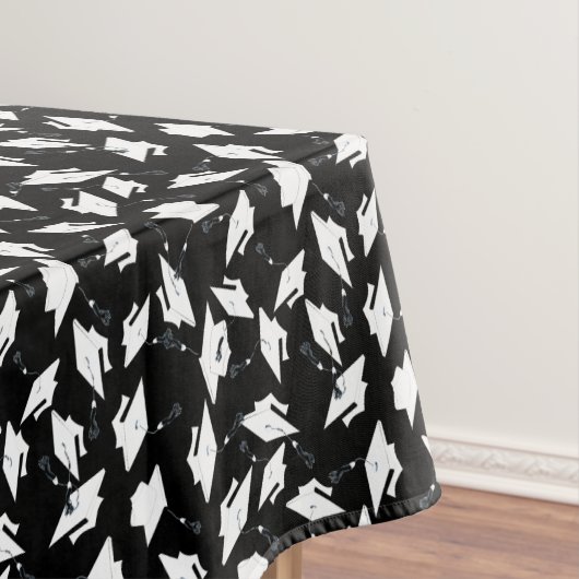 Witte afstudeerdopjes gegooid in de lucht op zwart tafelkleed (Voorbeeld)