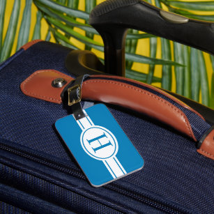 Witte band en ovaalschild met monogram op blauw bagagelabel