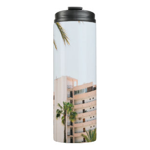 WITTE CONCRETE BOUW BESIDE GROENE PALM TREE UND THERMOSBEKER
