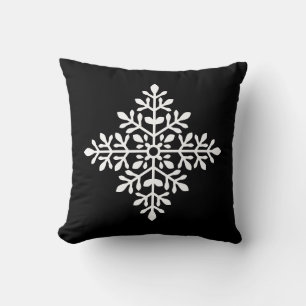 Witte decoratieve sneeuwvlok silhouet op zwart kussen