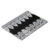 Witte kant vormt een delicate grens tegen zwart notitieboek (Linkerzijde)