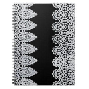 Witte kant vormt een delicate grens tegen zwart notitieboek