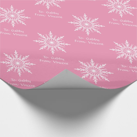 Witte sneeuwvlokken op roze cadeaupapier (Hoek)
