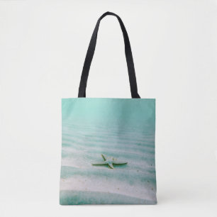 Witte zeester op zand onder water in de ochtend tote bag