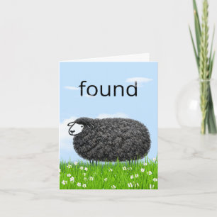 Wollig zwart schaap in gras met "gevonden" tekst kaart
