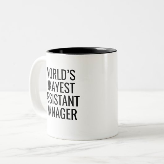 World's Okayest Assistant Manager Tweekleurige Koffiemok (Voorkant links)