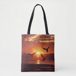 Zeemeeuwen die onder een gouden zonsondergang vlie tote bag