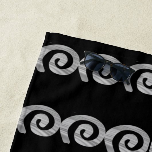 Zilveren spiralen patroon op zwart strandlaken (In situ)