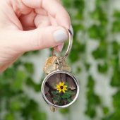 Zonnebloem groeiend uit gebarsten modder sleutelhanger (Hand)