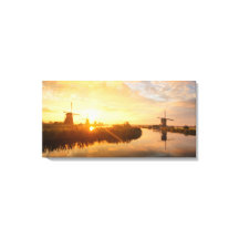 Zonneopstand boven windmolens en een rivier in Ned