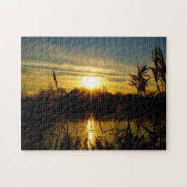 Zonsondergang bij een meertje met rietpluimen. legpuzzel
