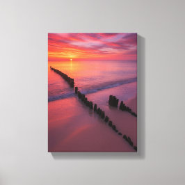 Zonsondergang over het strand met houten palen canvas afdruk