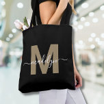 Zwart Goud Trendy Modern Script Naam Monogram Tote Bag<br><div class="desc">Gepersonaliseerde Elegant Zwart Goud Trendy Modern Script Naam Monogram Canvas tas. Voeg een vleugje glamour en sophisticatie toe aan uw dagelijkse stijl met deze chique canvas tas. Met een strak gouden initiaal (let op: het is een platte kleur, zonder glinstering of folie) gecentreerd op een heldere zwarte achtergrond en een...</div>