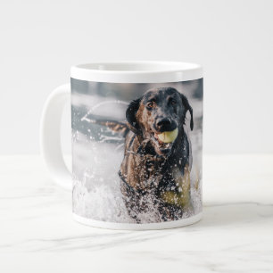 Zwart labrador speelt fets in water grote koffiekop