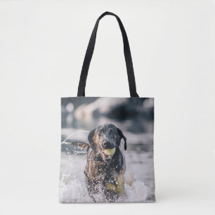 Zwart labrador speelt fets in water tote bag