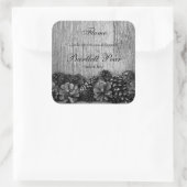 Zwarte dennenappels op rustiek houten kaars label (Tas)