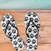 Zwarte dog schildert afdrukken op wit teenslippers