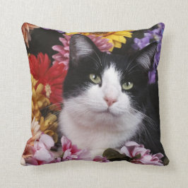 Zwarte en witte kat op bloemen kussen