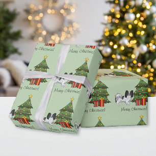 Zwarte en witte papillon hond bij een kerstboom cadeaupapier