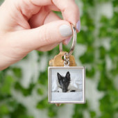 Zwarte en witte puppy in bed met bot sleutelhanger (Hand)