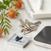 Zwarte en witte puppy in bed met bot sleutelhanger (Zijkant)
