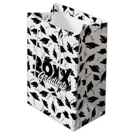 Zwarte gradatiekappen getoseerd in de lucht op wit medium cadeauzakje