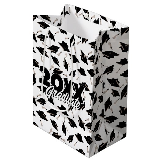 Zwarte gradatiekappen getoseerd in de lucht op wit medium cadeauzakje (Voorkant Gekanteld)