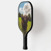 Zwarte hoogland koe grazend groen veld zonlicht pickleball paddle (Links)