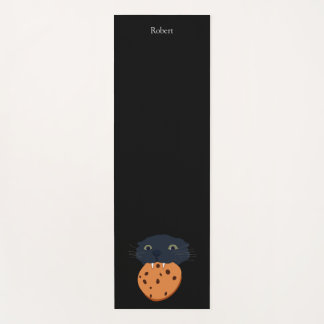 zwarte kat houdt een koekje vast yogamat