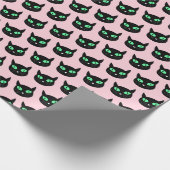 Zwarte kat met groene ogen op pastelroze cadeaupapier (Hoek)