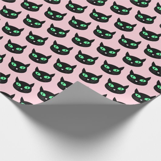 Zwarte kat met groene ogen op pastelroze cadeaupapier (Hoek)