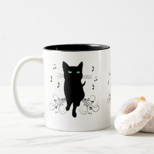 Zwarte kat omringd door fluisterende muzieknoten tweekleurige koffiemok