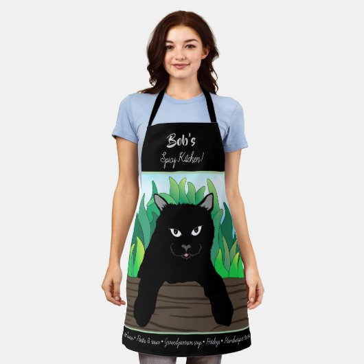 Zwarte kat op hek met groen gras schort (Gedragen)