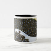 Zwarte kaviaar en een lepel van een parelmoer tot tweekleurige koffiemok (Center)