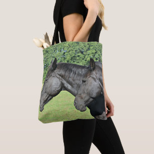 Zwarte paarden op een door de zon verlichte weide tote bag